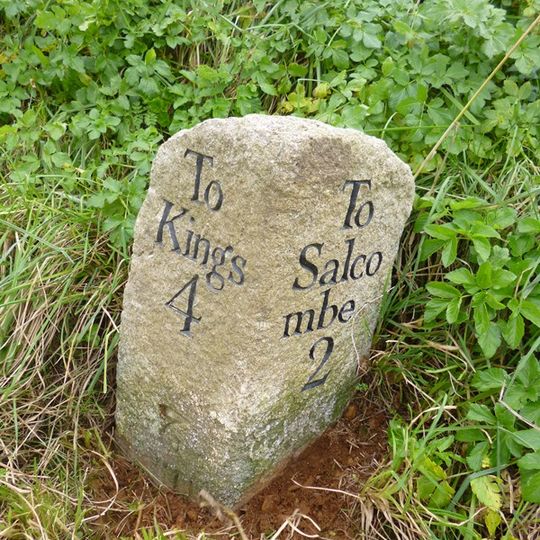 Milestone, Salcombe Road, 350m E of village, just S of entrance gate, on bank below cycle path
