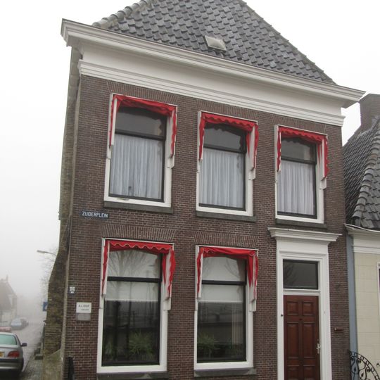 Diep hoekpand met omlijste deur en eenvoudige rechte kroonlijst onder schilddak