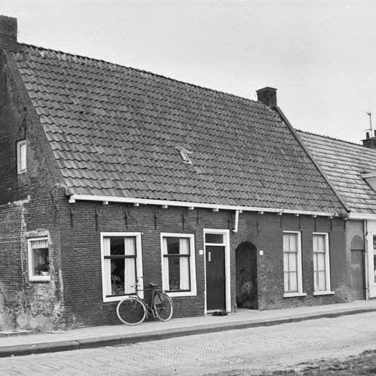 Hofje met hoofdgebouw onder zadeldak evenwijdig aan de straat tussen twee topgevels