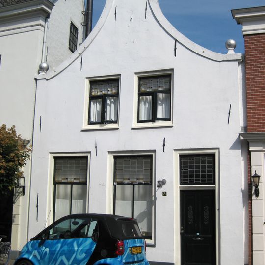Witgepleisterd pand met afgeknotte klokgevel
