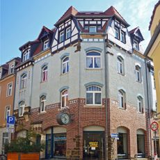 Mietshaus mit Ladenzone in Ecklage mit Anbau zur Berggasse und Werbeausleger mit Uhr Hauptstraße 21