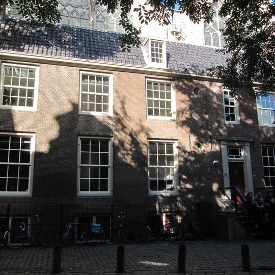 Tegen de zuidzijde van de oudekerk gebouwd dwars huis onder zadeldak
