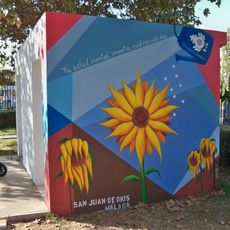 El mural realizado con motivo del Día de la Salud Mental. Muestra cuatro girasoles: tres de ellos marchitos y uno floreciendo revitalizado por el agua que cae de una regadera con las siglas «SJD», en alusión al Centro Asistencial San Juan de Dios.