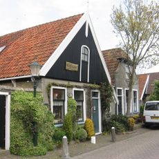 Pand onder zadeldak met houten voorschot waarin luik Kosterij van Doopsgezinde Kerk. Tuinschutting met poortje