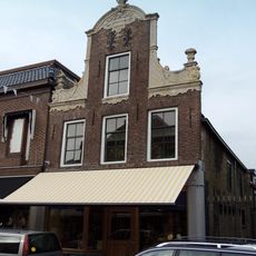 Pand met zadeldak tegen halsgevel met gebeeldhouwde klauwstukken en bekroning in de Friese Lodewijk XIV-stijl