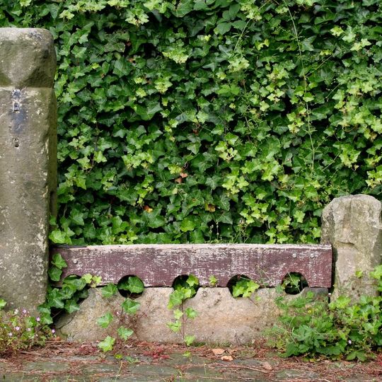 Stocks Approximately 5 Metres North Of East Gate To Church