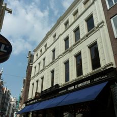 Pand met gevel onder bijzondere, grote zandstenen top in de vorm van een halsgevel met gedeelde vleugelstukken, volutenafdekking en ornament om het zoldervenster