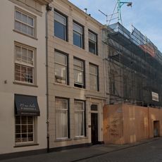 Huis met sobere gepleisterde lijstgevel. Ingangspartij met voluutvormige consoles onder kroonlijstje