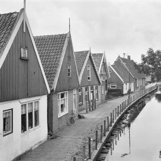 Woning aan de vaart onder zadeldak tegen topgevel met houten voorschot