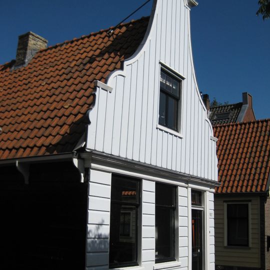 Houten dijkhuis huis met klokgevel uit 19de eeuw, houten puntgevel aan de achterzijde voorschot